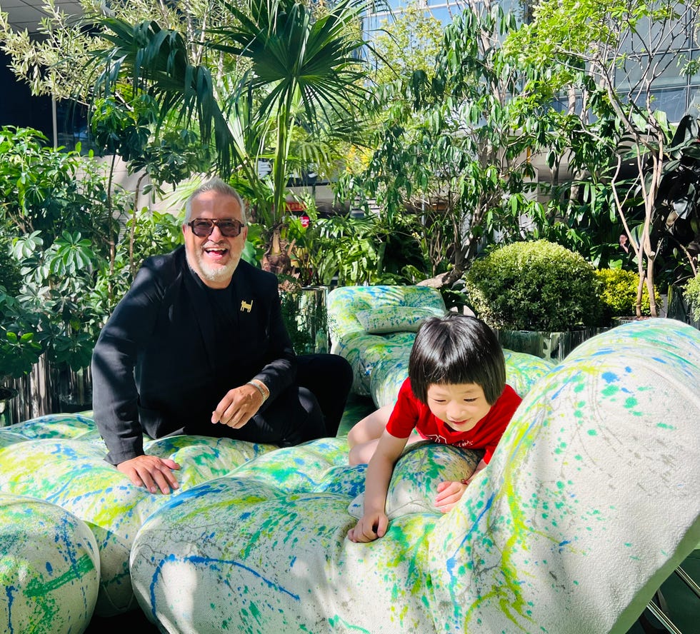 a seated person and a child on colorful cushioned furniture surrounded by greenery