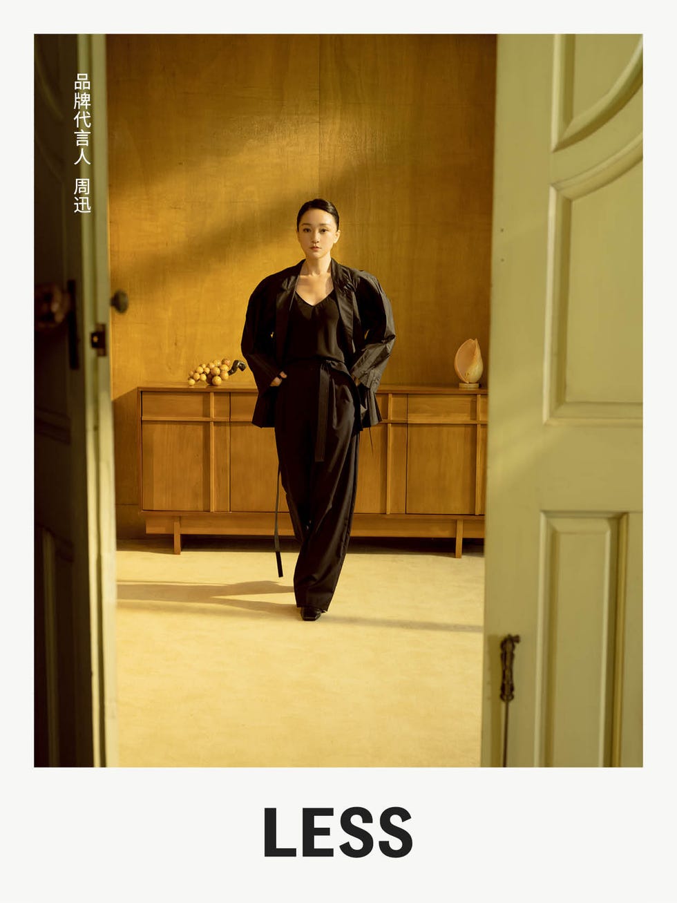 a person in a black outfit stands in an elegantly styled interior