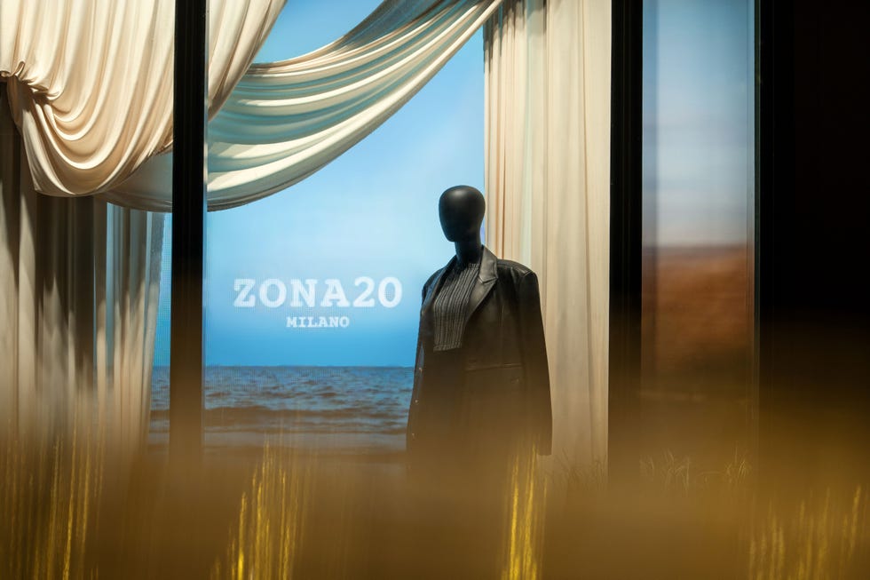 mannequin dressed in a black jacket against a backdrop featuring a coastal scene