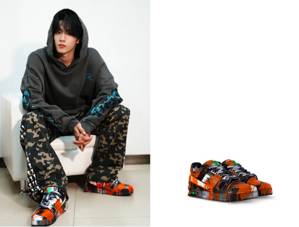 a person is sitting wearing a hooded sweatshirt and camo pants showcasing vibrant sneakers