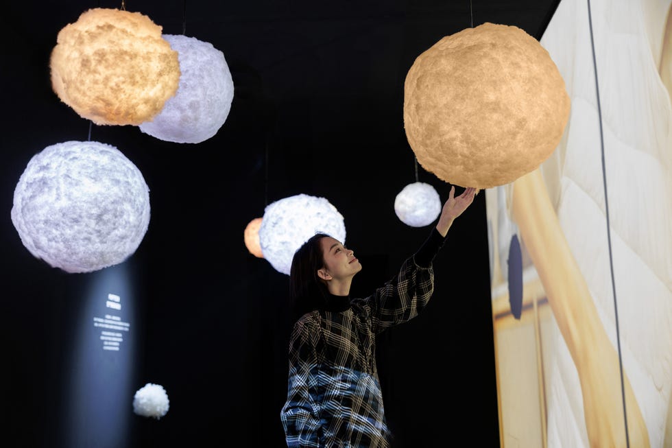 hanging illuminated spheres in a dark space with a person reaching towards one